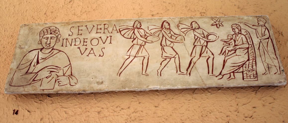 Laje de sarcófago, proveniente das Catacumbas de Roma (século III). A inscrição contém uma súplica por uma defunta: “Severa, que vivas em Deus”. À direita, três figuras vêm trazer presentes ao Menino Jesus, no colo de sua Mãe.
