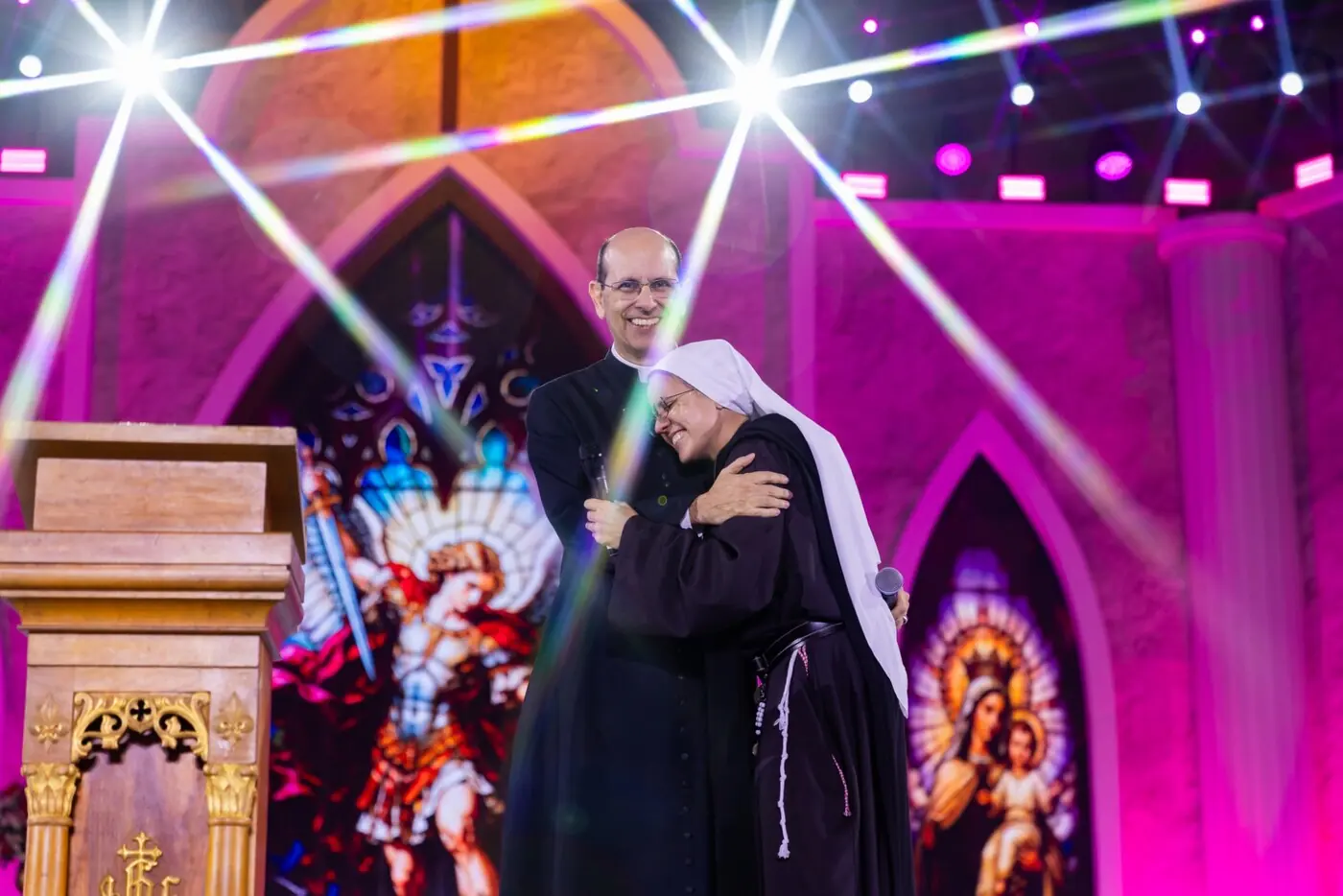 Padre Paulo Ricardo abraçado a uma religiosa no palco de um encontro